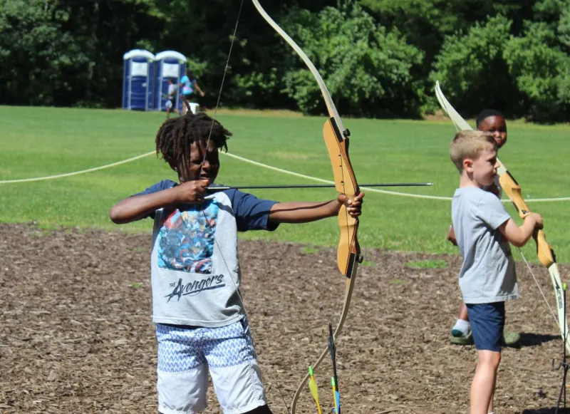 Campers practicing archery on the field