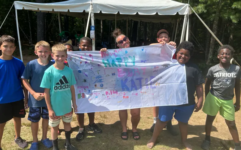 A group of campers holding up a painted banner