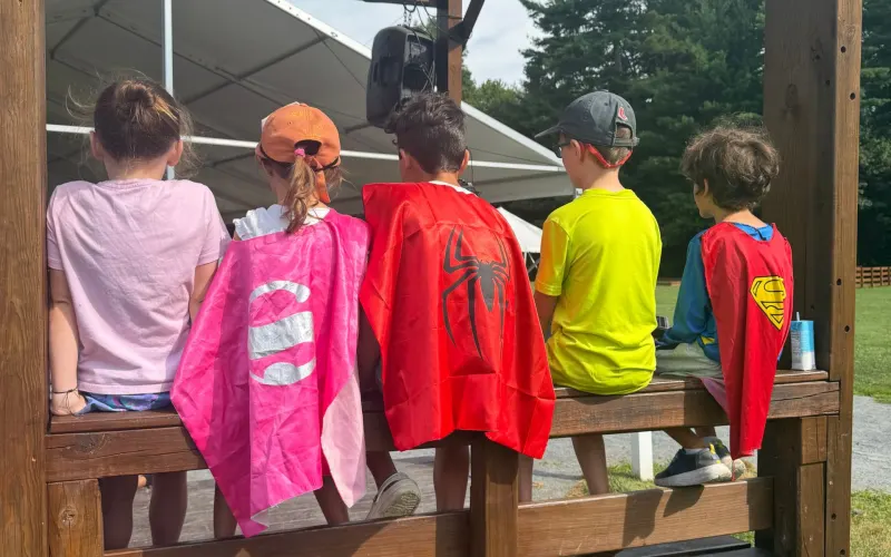 Campers in capes sitting on a bench under a pavilion