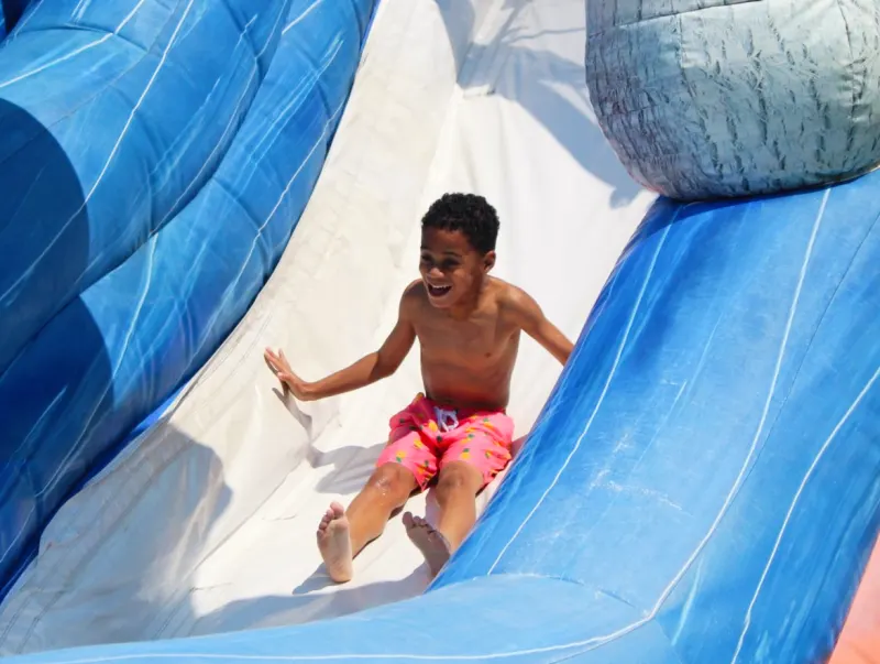 A camper sliding down a blue inflatable slide