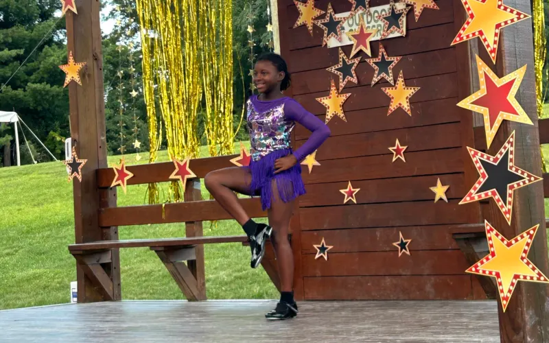 A camper posing on a star-covered stage